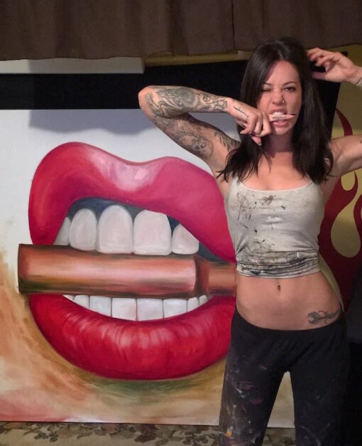 alexa jacobs working on a painting of lips and teeth biting a gold bullet