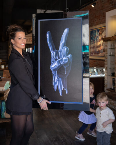 Alexa Jacobs holding her painting of a melted hand doing the peace sign