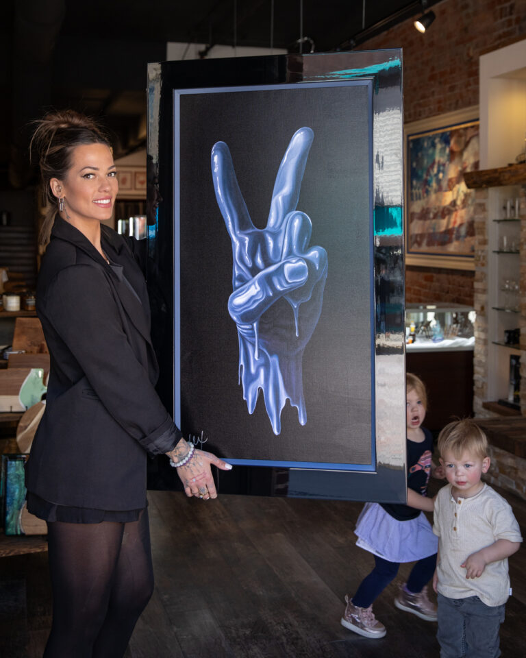Alexa Jacobs holding her painting of a melted hand doing the peace sign