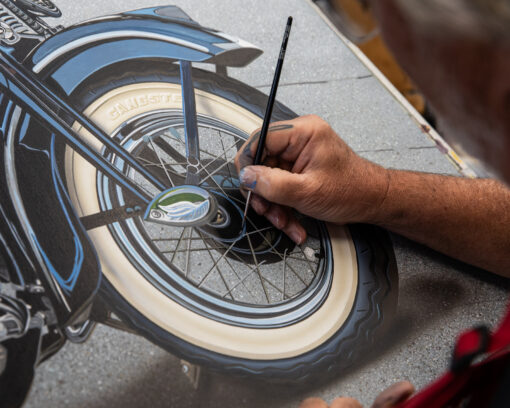 Scott Jacobs painting the wheel of his 2025 Sturgis rally motorcycle painting