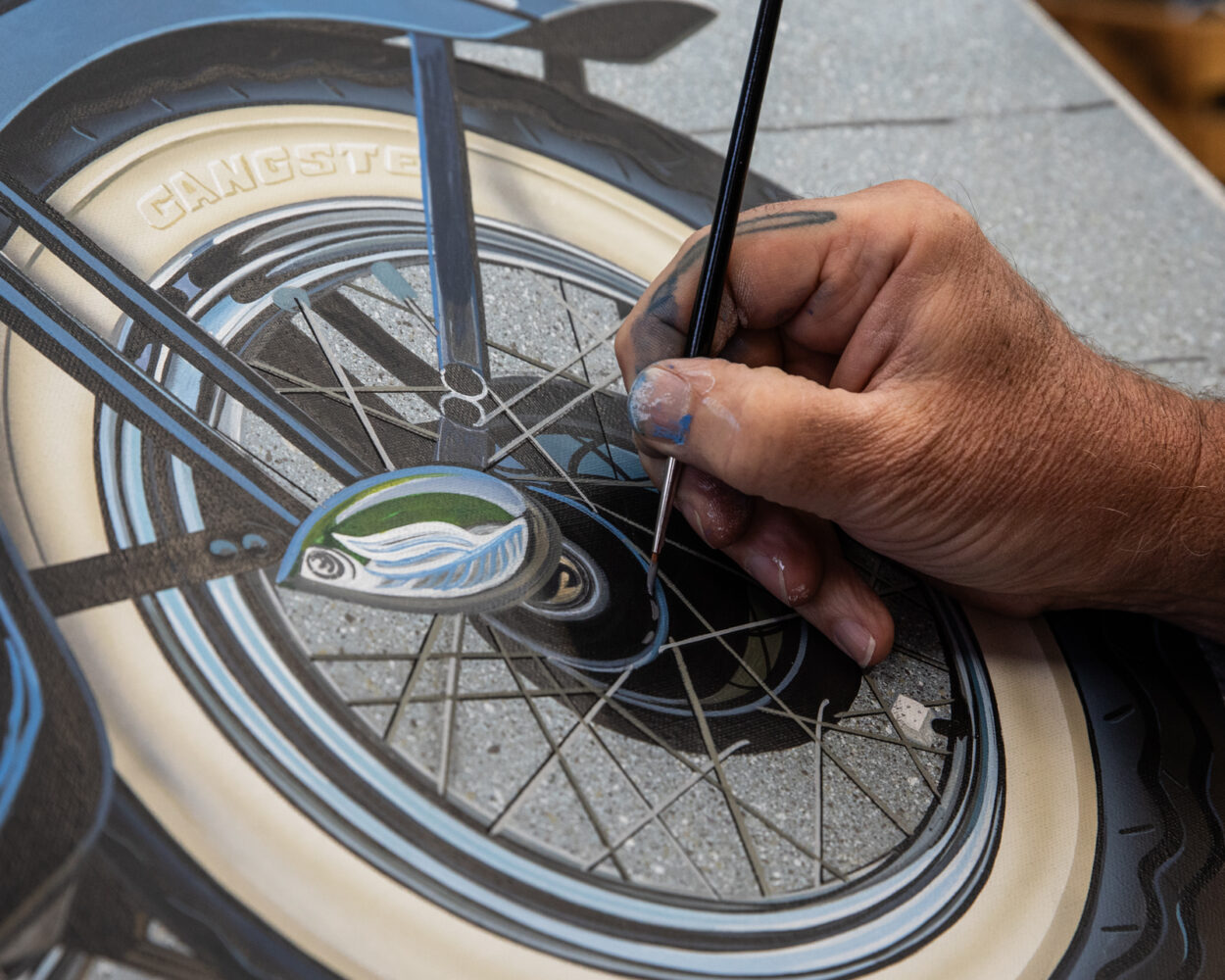 close up of Scott jacobs working on his 2025 Sturgis motorcycle and plane painting, America's beauties